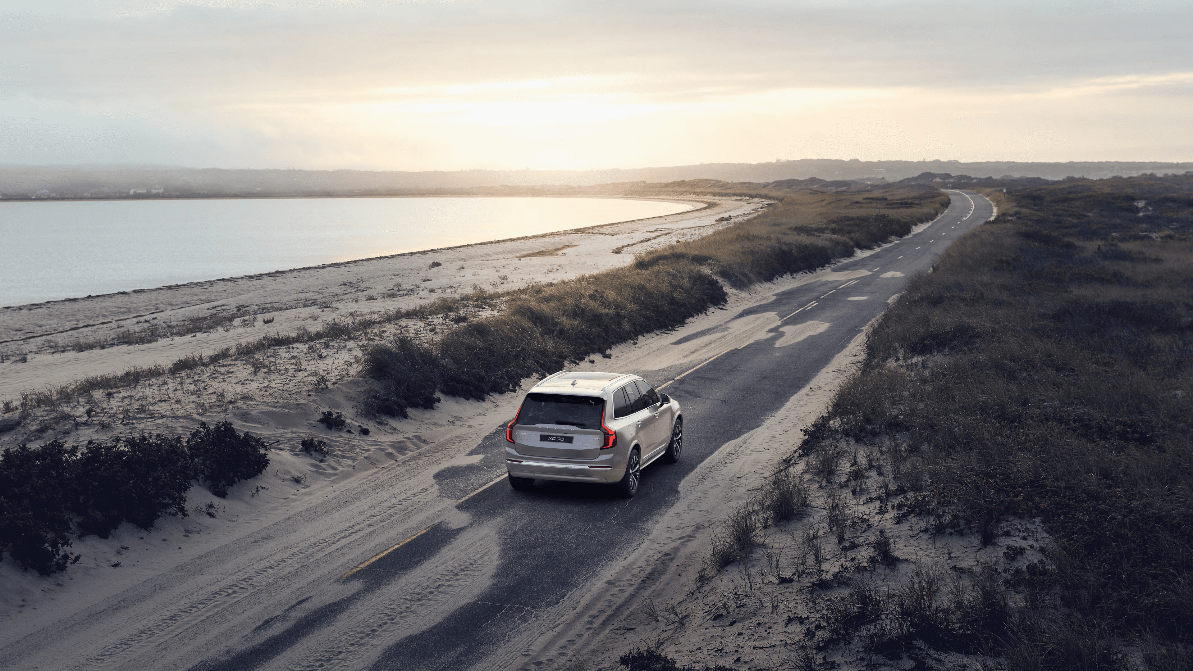 Volvo XC90 percorrendo uma estrada litorânea ao entardecer