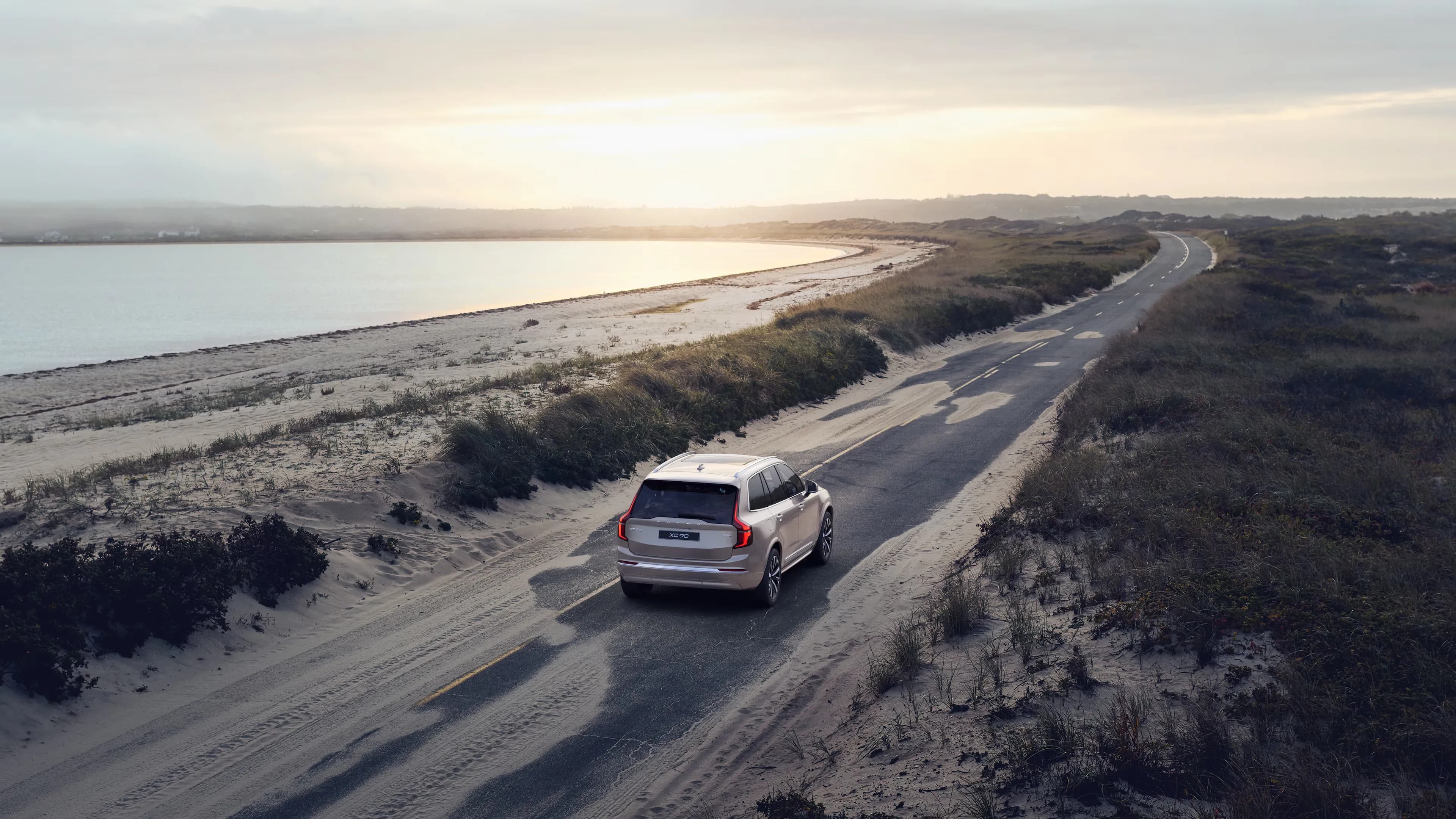 Volvo XC90 percorrendo uma estrada litorânea ao entardecer