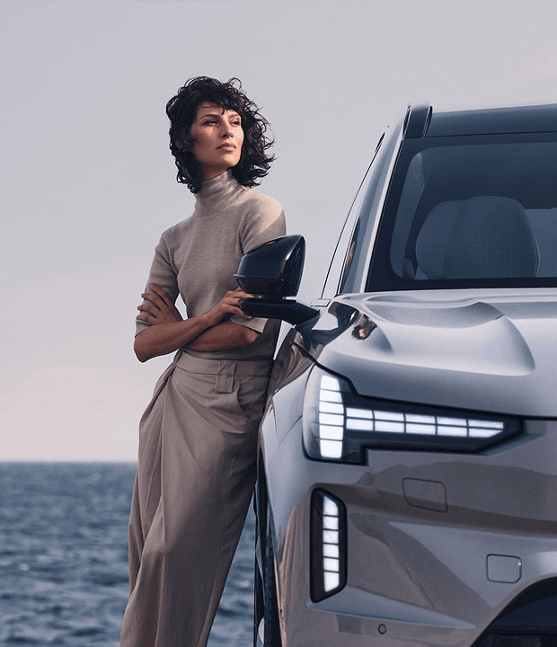 Mulher apoiada em um Volvo com vista para o mar